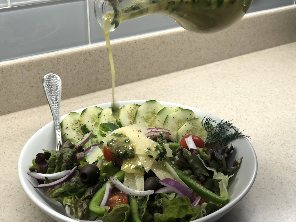 pouring pickle juice salad dressing on salad 