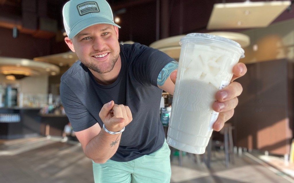 man holding starbucks cup with peaches and cream drink inside