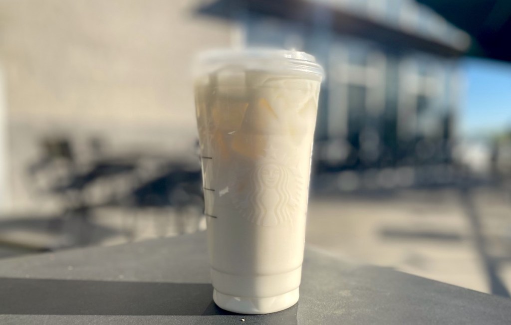 white drink in starbucks cup sitting on table outside