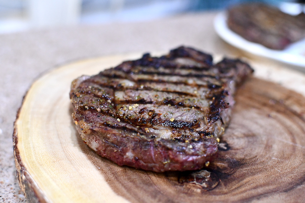 large grilled ribeye steak on cutting board