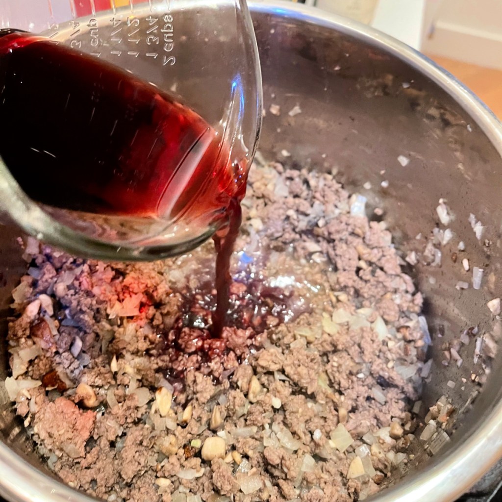 wine being poured into cooked ground beef