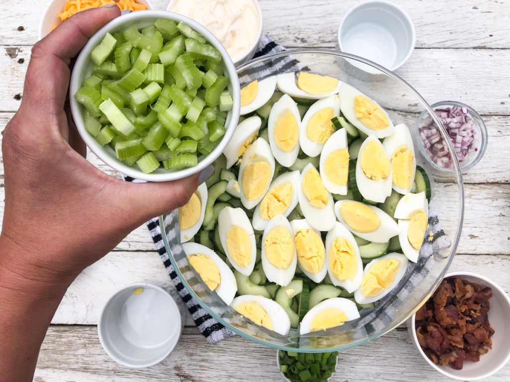 adding cucumbers to salad with hard boiled eggs