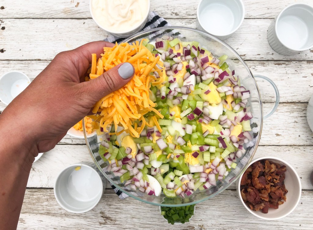 putting a handful of cheese on a keto 24 hour salad