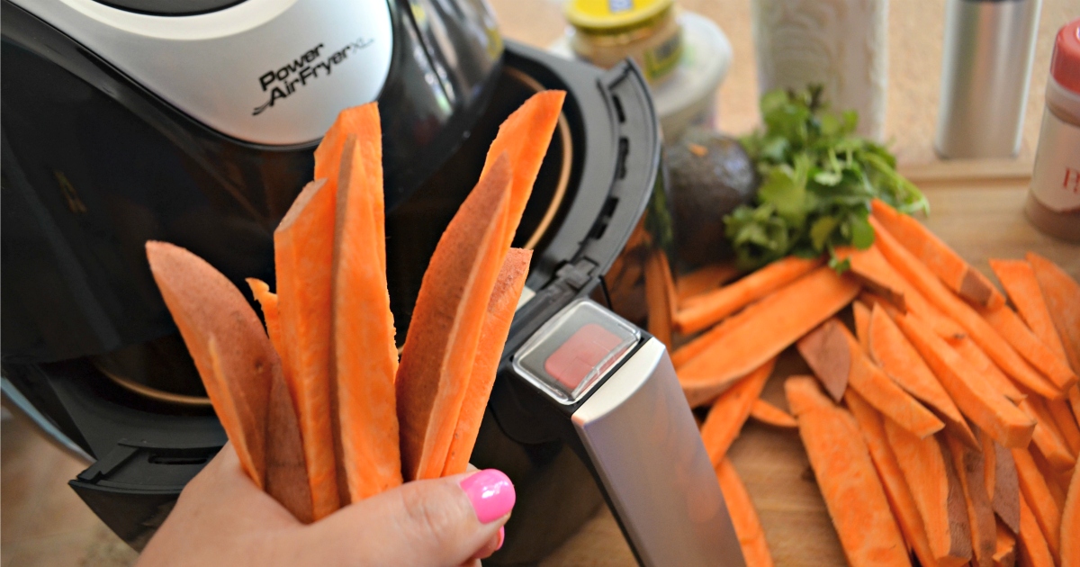 holding cut sweet potatoes next to air fryer