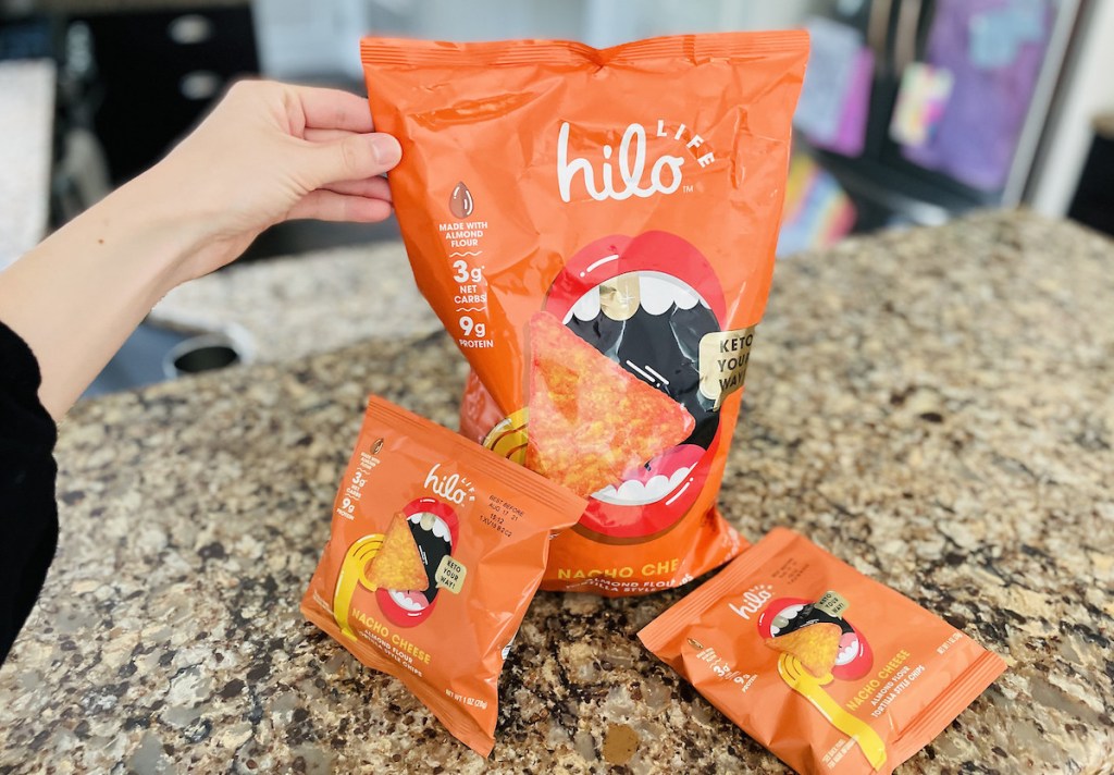 hand holding large bag of hilo chips on kitchen counter next to smaller bags