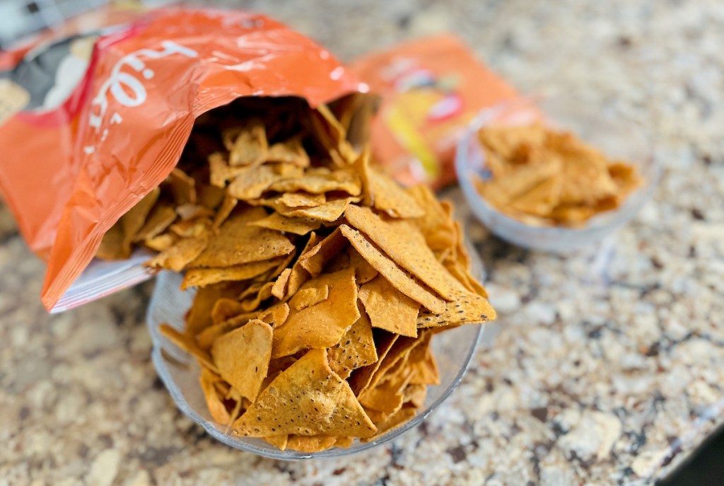 large and small bags of keto chips on granite counter spilling into clear bowls