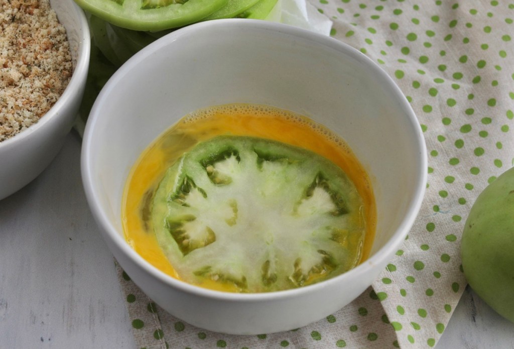 green tomatoes in keto egg wash in bowl
