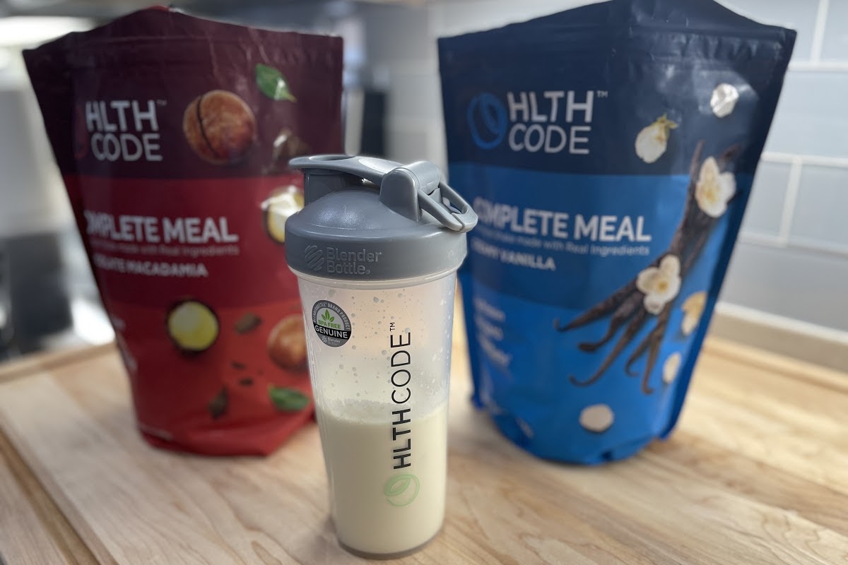 two bags of meal replacement powder on counter behind tumbler