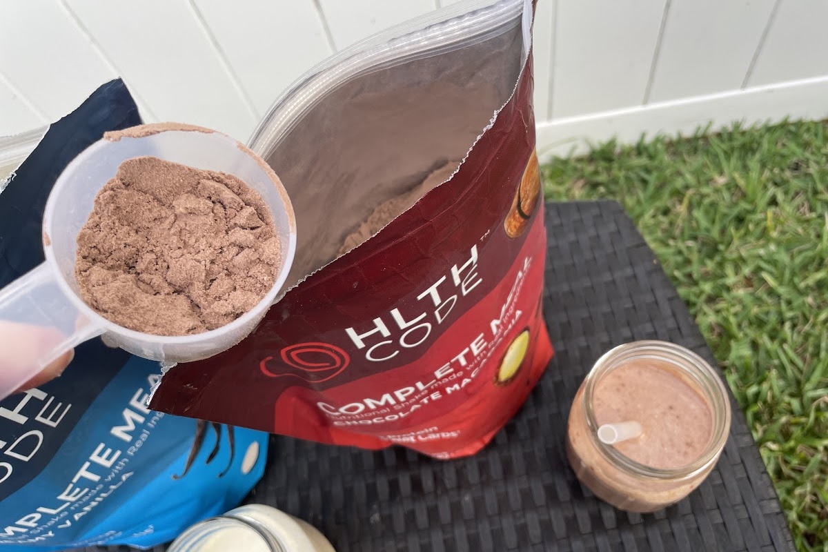 scoop of meal replacement powder being held over bag