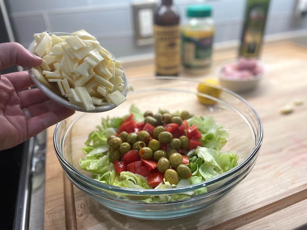 putting cheese and olives in salad