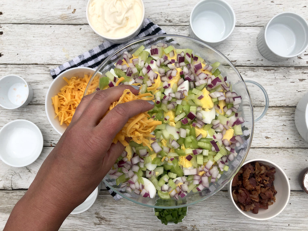 putting toppings on 24 hour salad