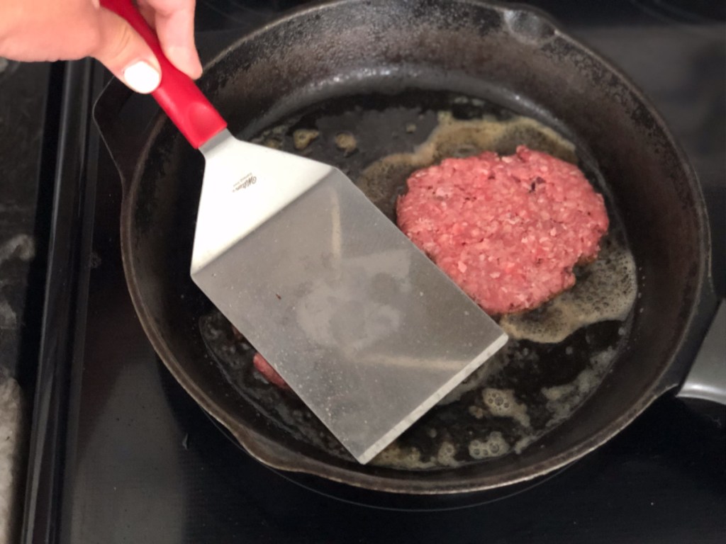 smashing burgers in a skillet
