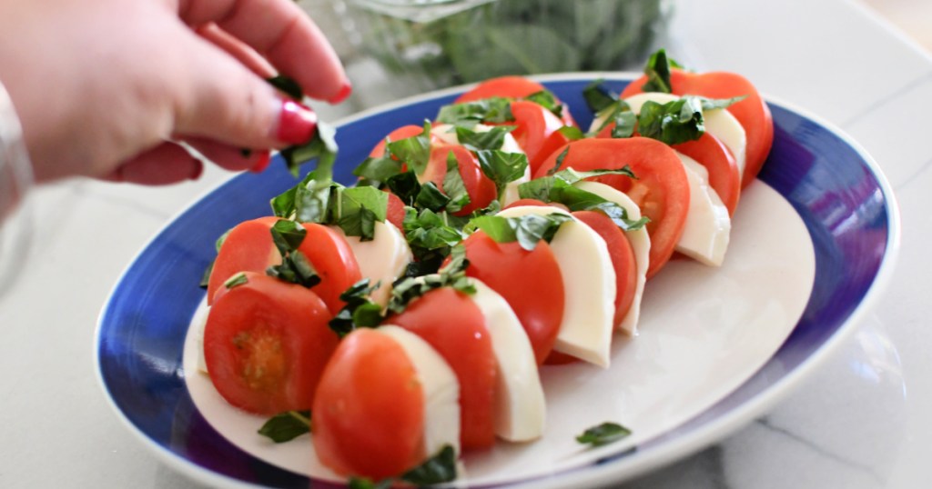 adding basil to caprese salad