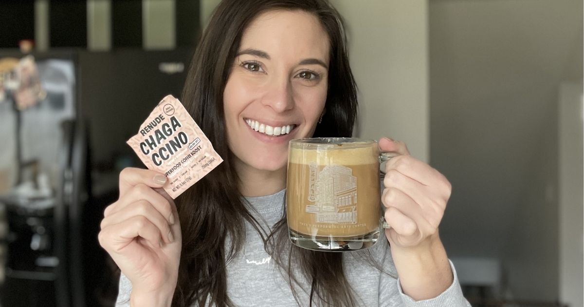 woman holding a cappuccino made with chaga and a Renude Chagaccino packet