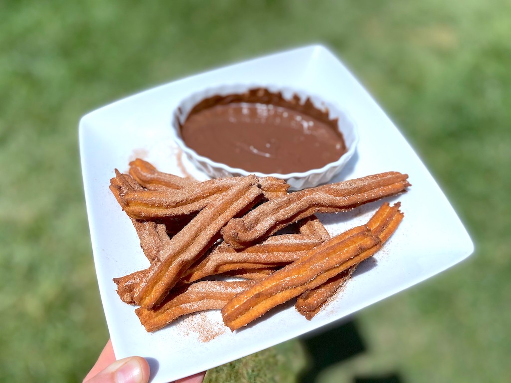 holding plate of keto churros with chocolate dipping sauce 