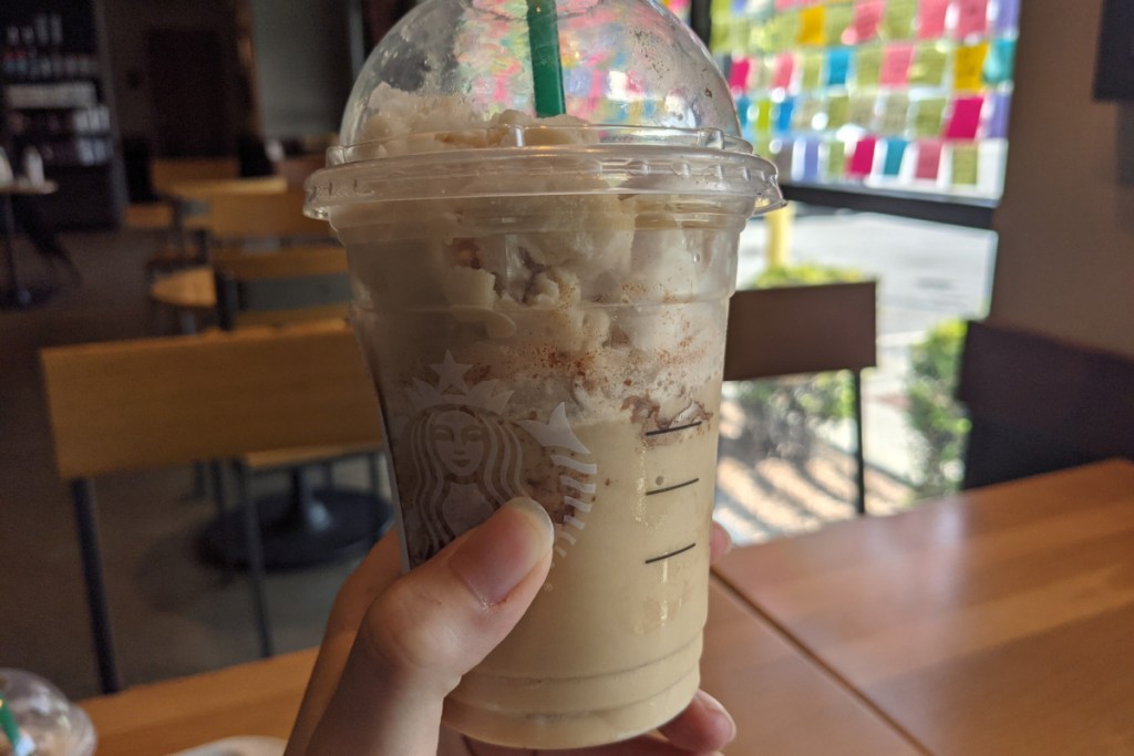 Hand holding keto cinnamon dolce frappuccino in Starbucks store