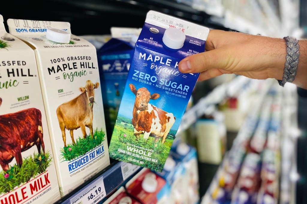 Hand pulling out a carton of Maple Hill zero sugar milk