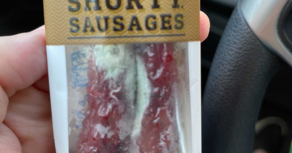 hand holding package of moldy smoked sausages
