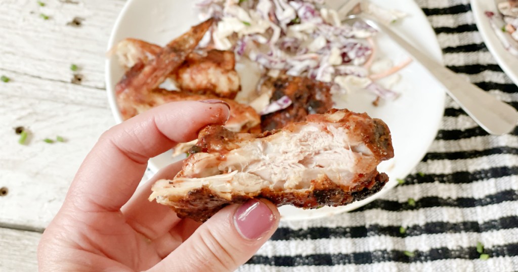 holding a piece of keto bbq chicken