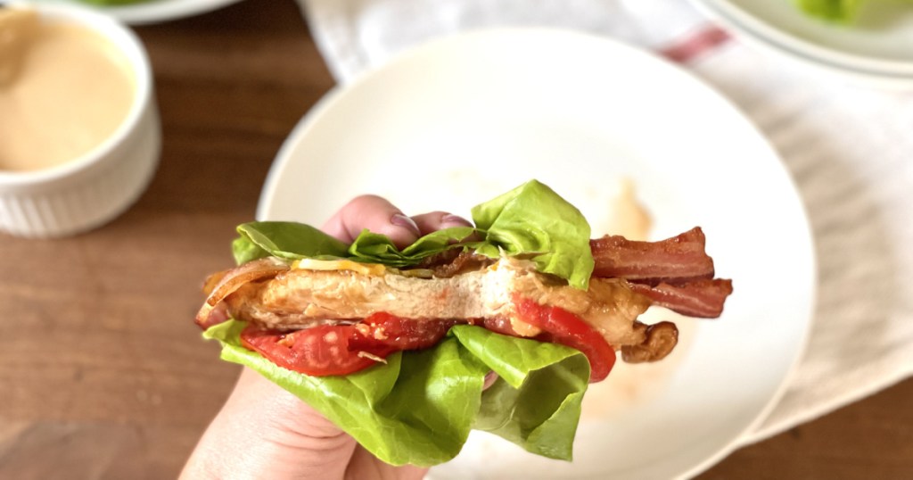 holding keto chick-fil-a grilled chicken sandwich in lettuce wrap