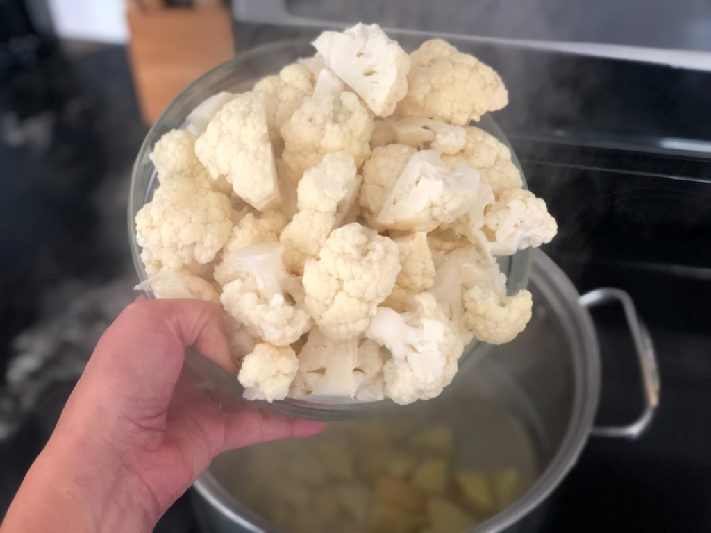 adding cauliflower to a stockpot