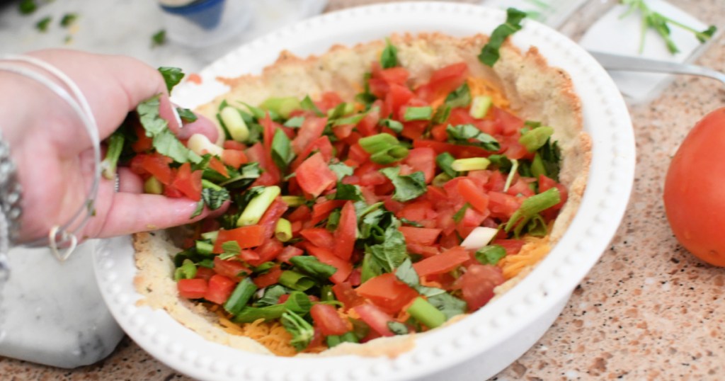 adding tomatoes and basil to tomato pie