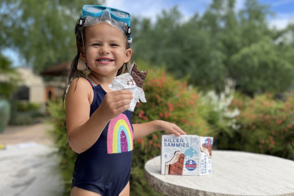 girl eating keto ice cream sandwich near pool