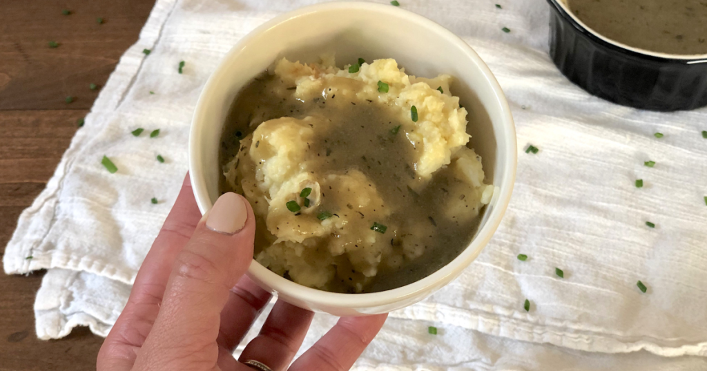 holding bowl of mashed potatoes and gravy