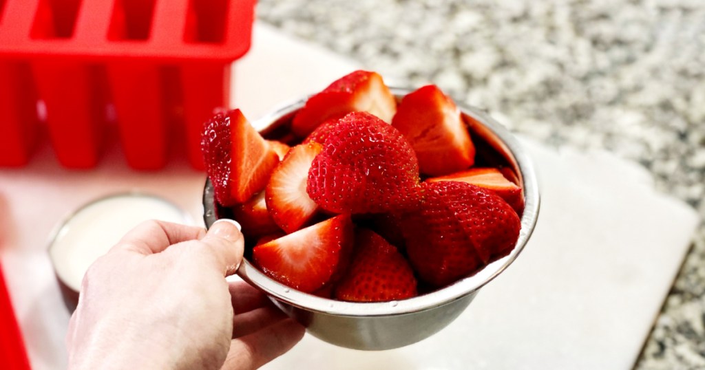 hand holding small bowl of strawberries