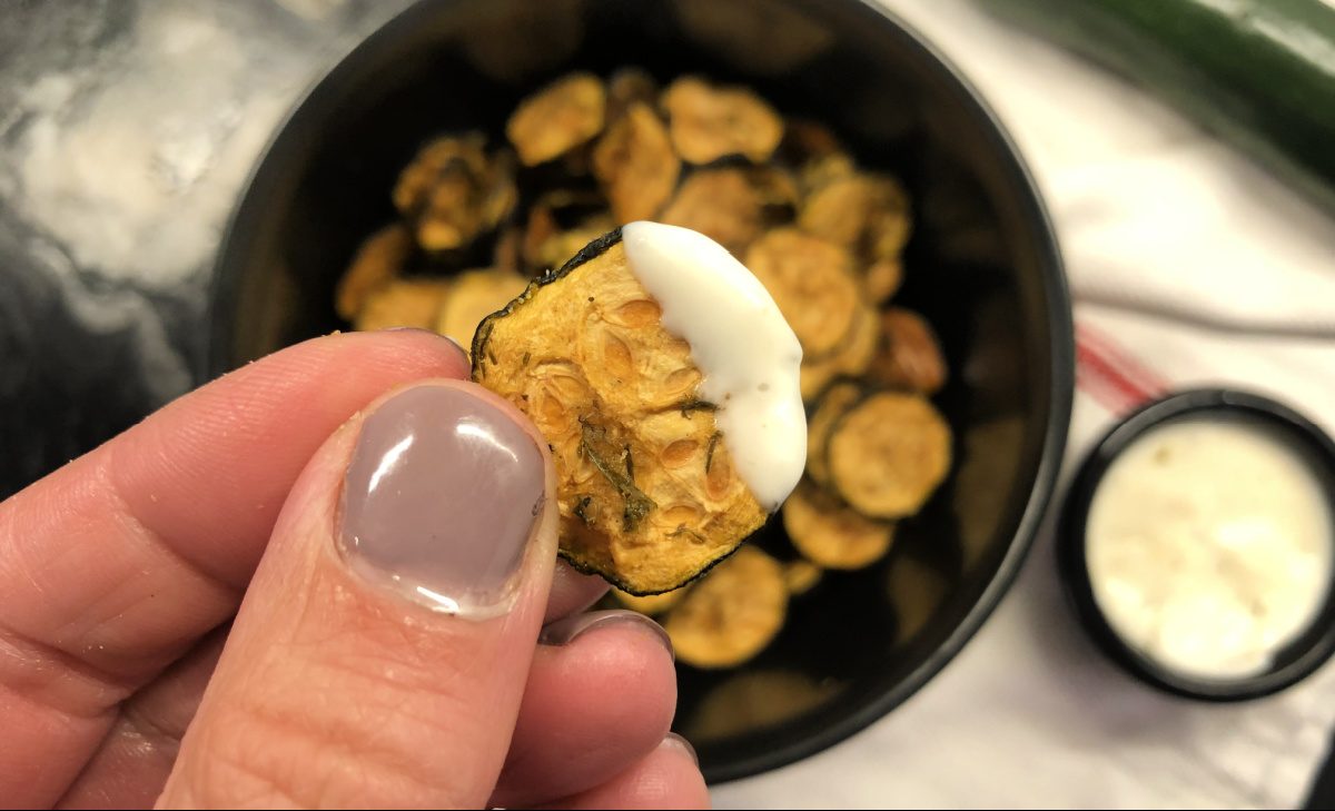 hand holding a keto zucchini chip dipped in ranch
