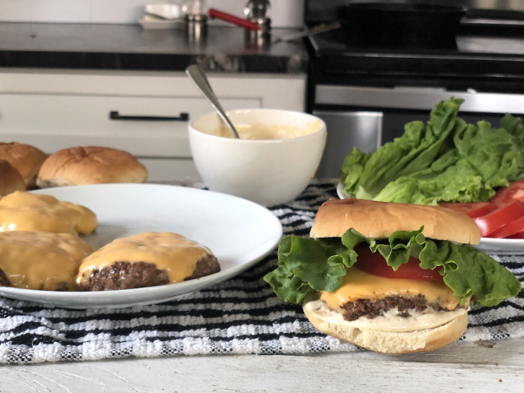 Shake Shack cheeseburger dupes on kitchen counter with lettuce and tomato