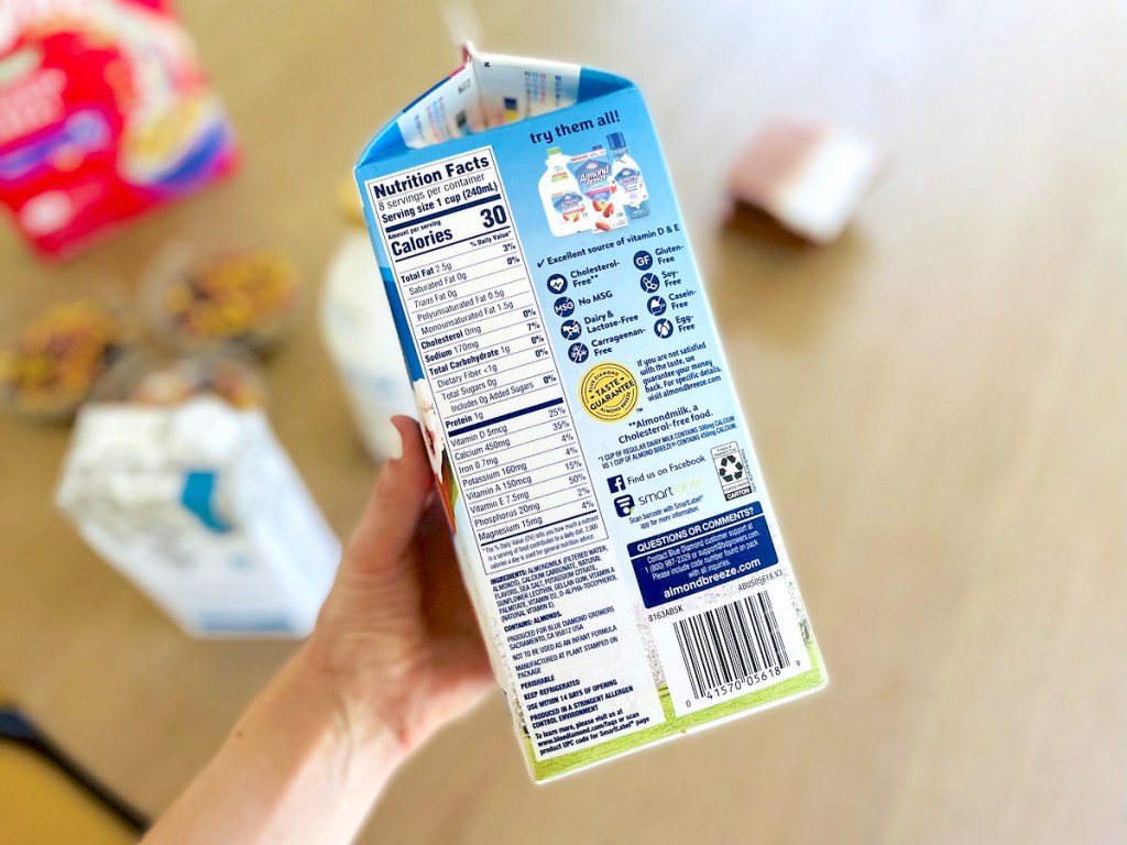 hand holding carton of unsweetened almond milk with ingredients label