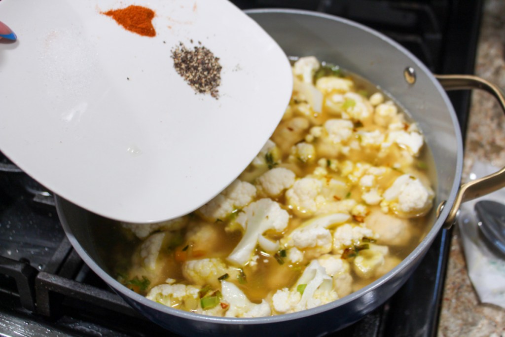 Adding spices to a pot of vegetables