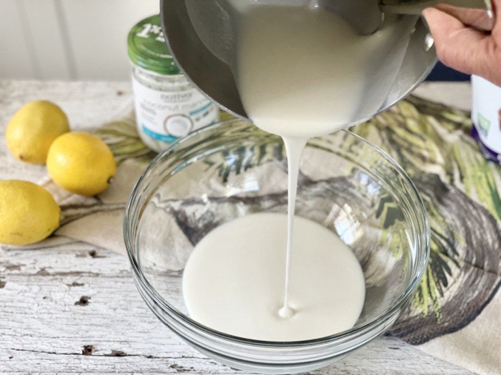 pouring melted coconut butter into a bowl for keto lemon fat bombs 