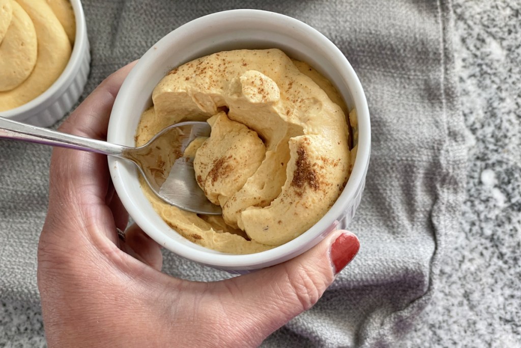 holding a ramekin of keto pumpkin mousse