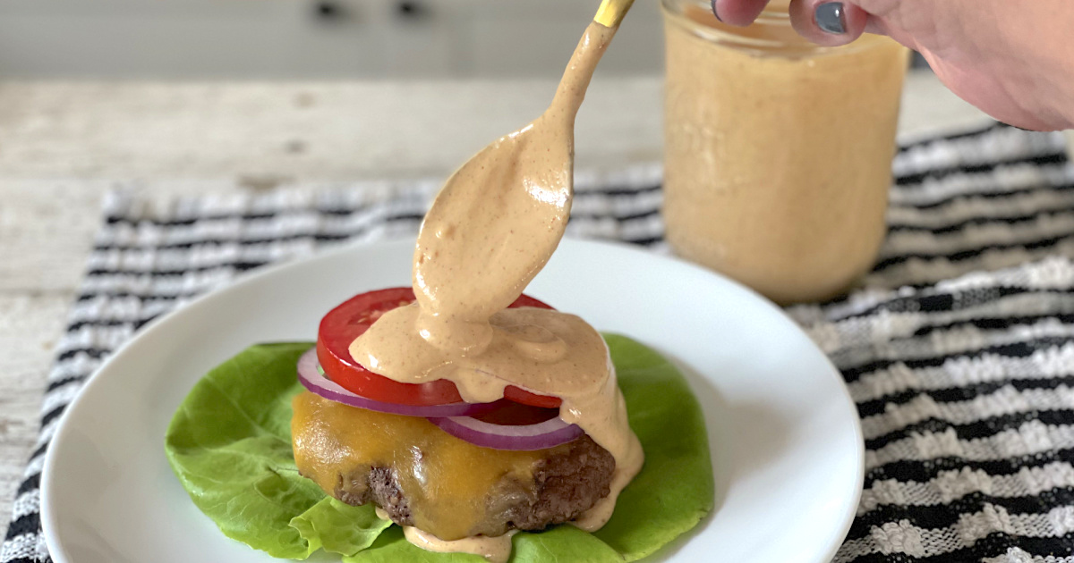 putting keto burger sauce on burger 