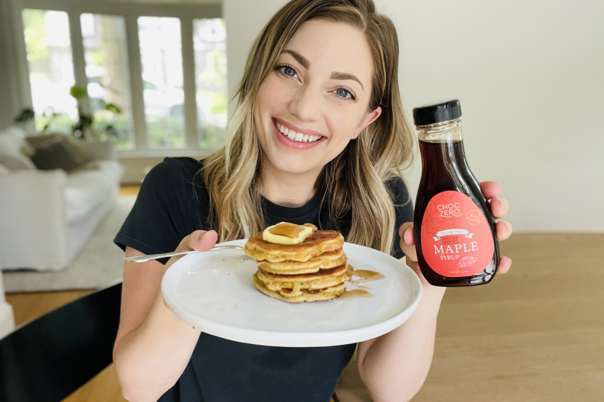 Woman holding pancakes and ChocZero keto syrup