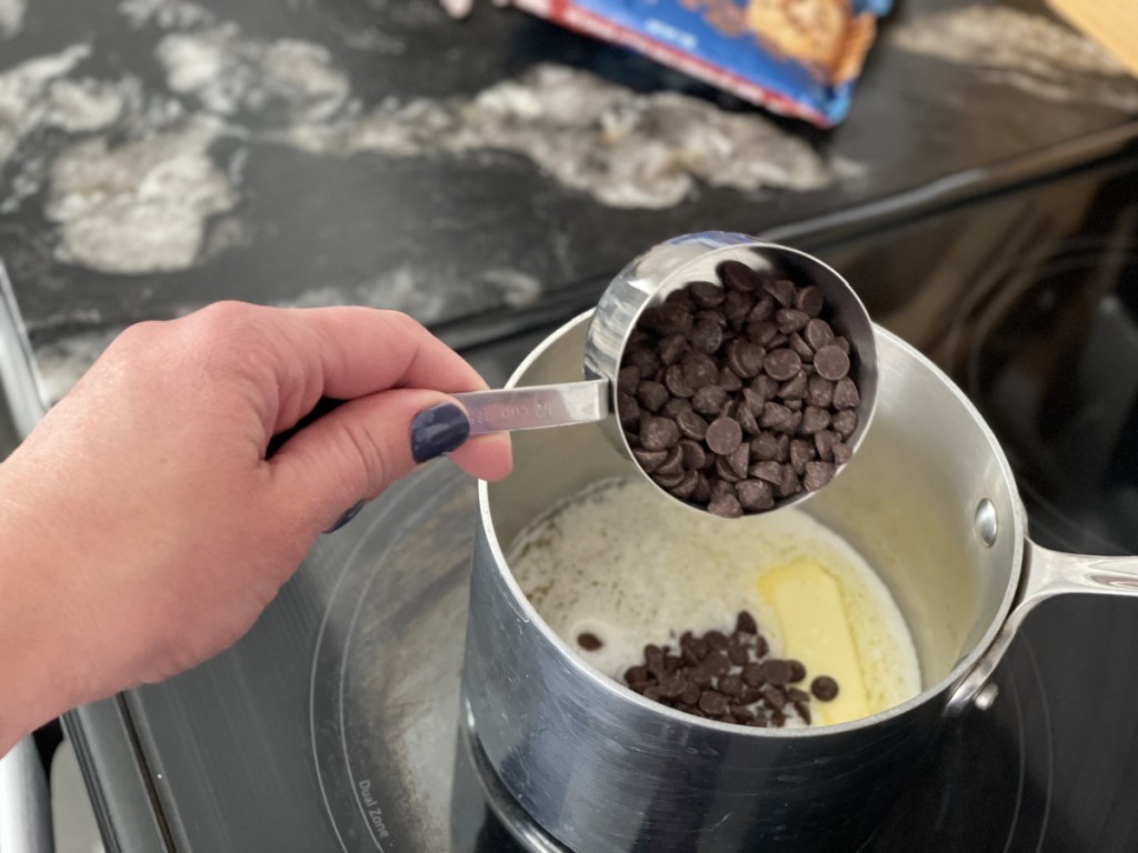 adding chocolate chips to a saucepan for Keto Kitchen Sink Brownies