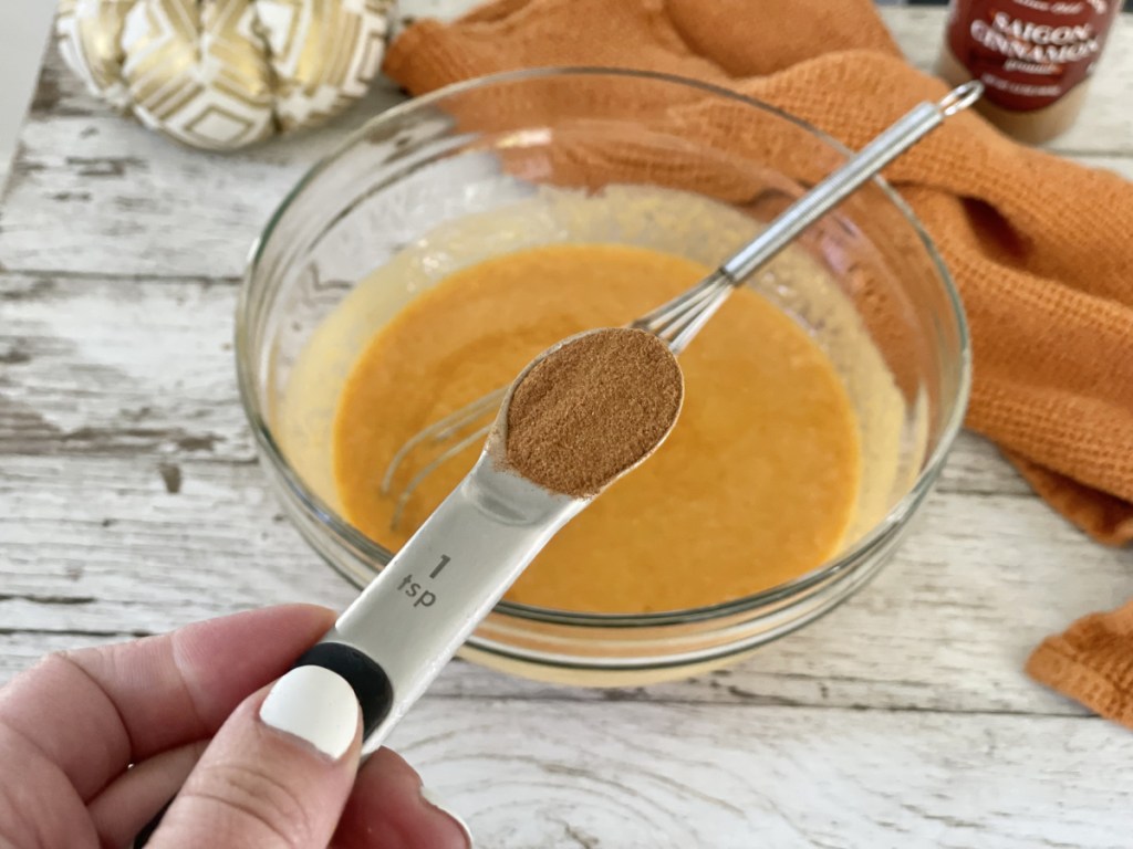 adding cinnamon to a mixing bowl for keto pumpkin bread