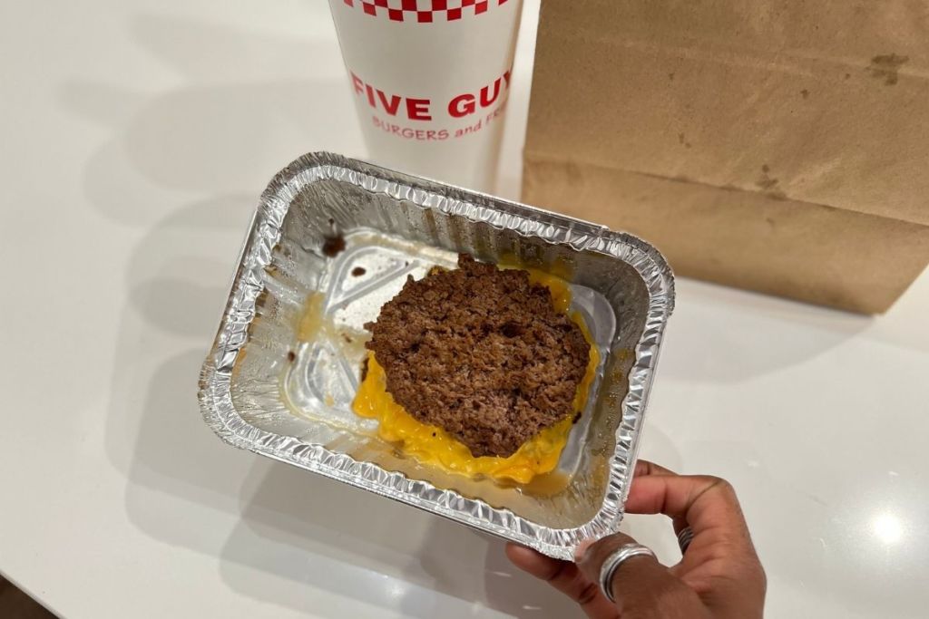 holding a Five Guys keto burger with no bun