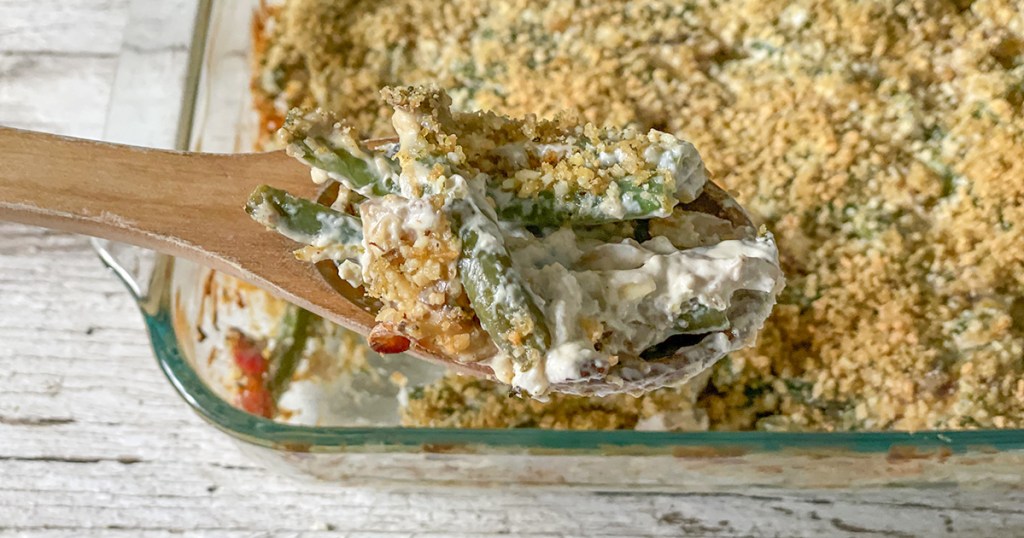 scoop of keto green bean casserole on wooden spoon