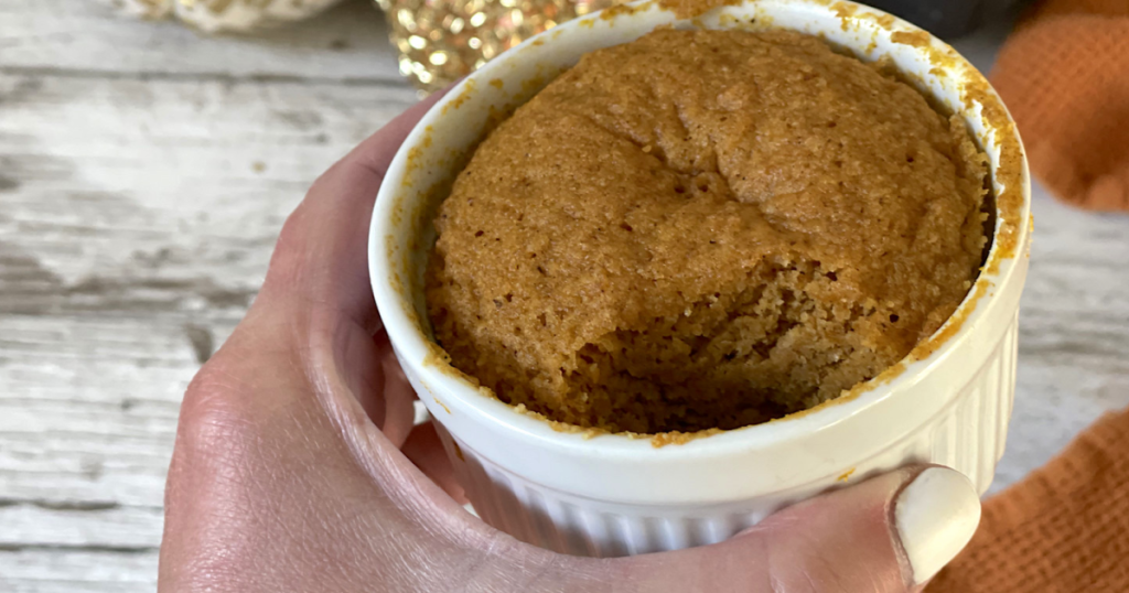 holding keto pumpkin mug cake with bite out of it