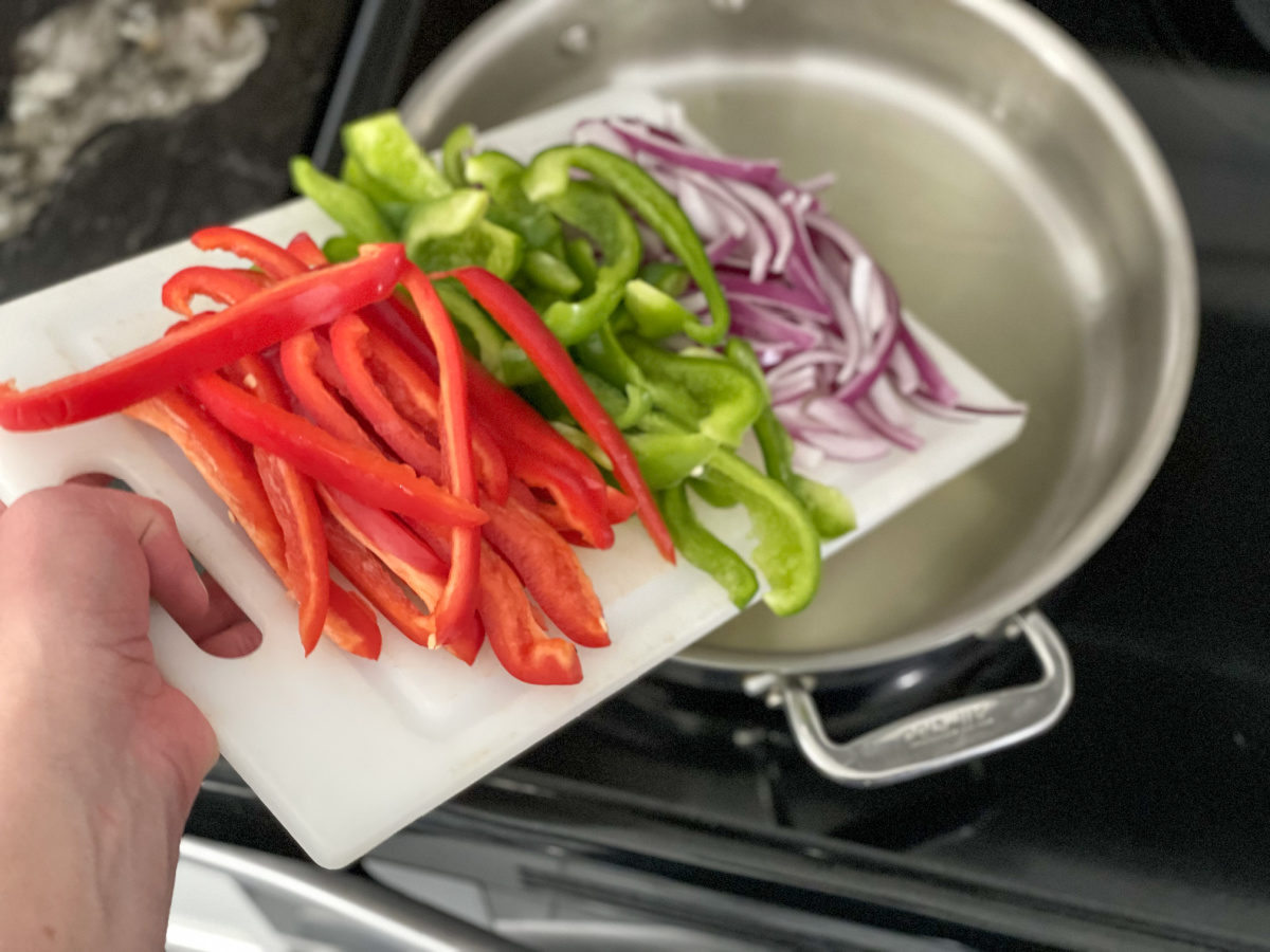 adding pepper and onions to a skillet 