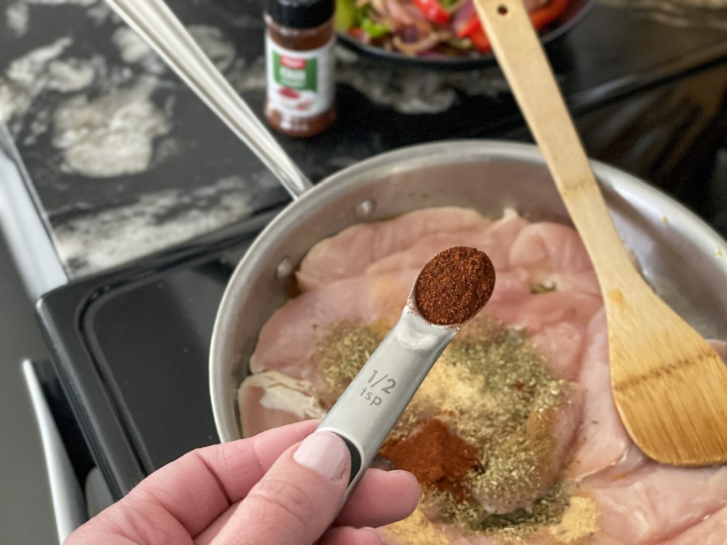 adding seasonings to chicken in a skillet for Easy keto skillet chicken fajitas