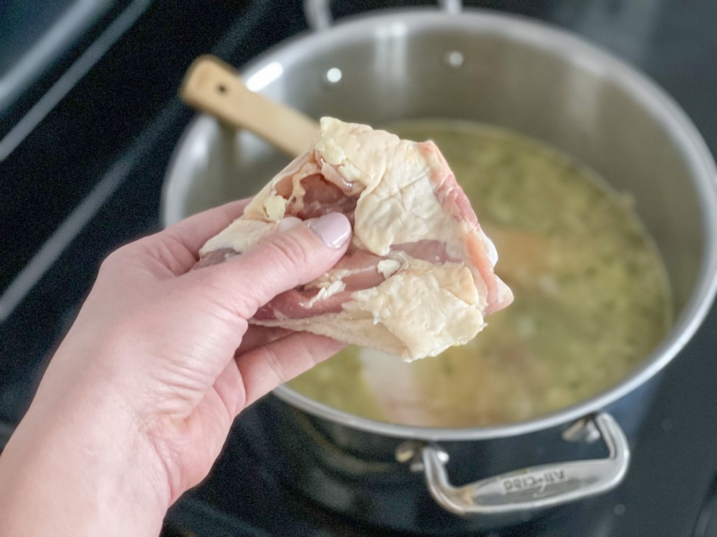 holding a chicken thigh to add to Keto Chicken Noodle Soup