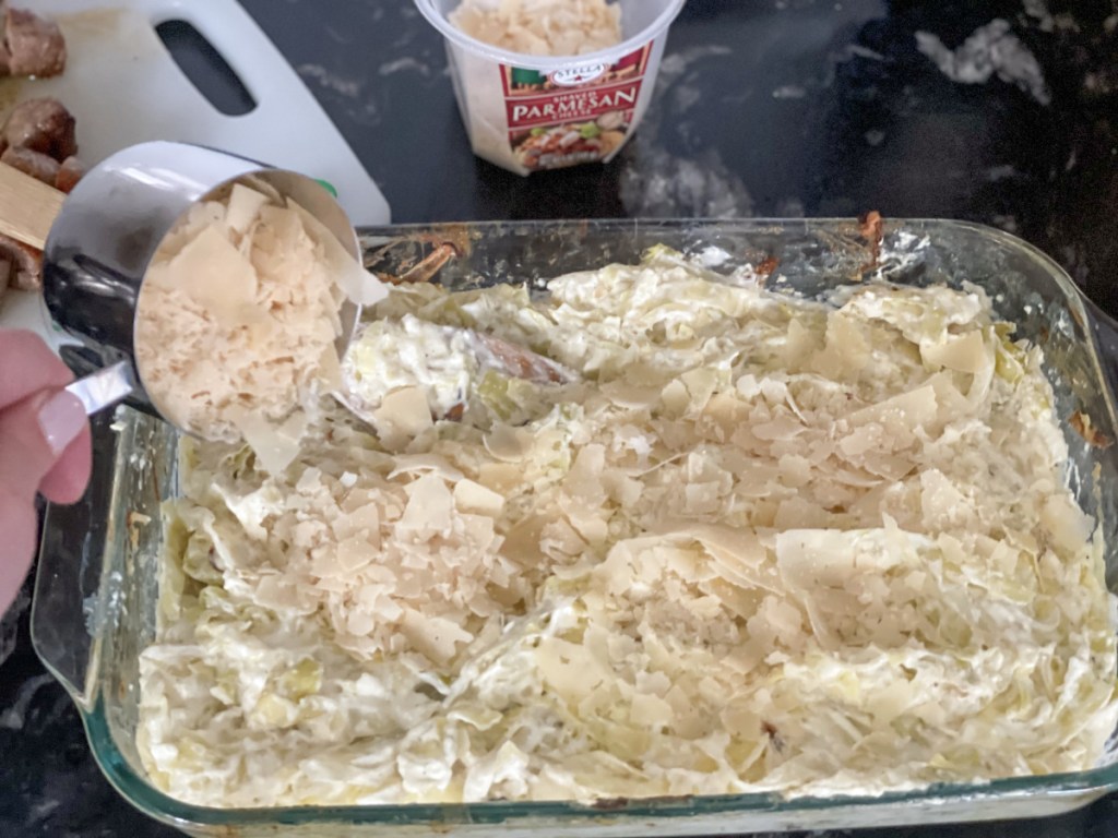 adding parmesan to Keto Sausage Alfredo with Cabbage