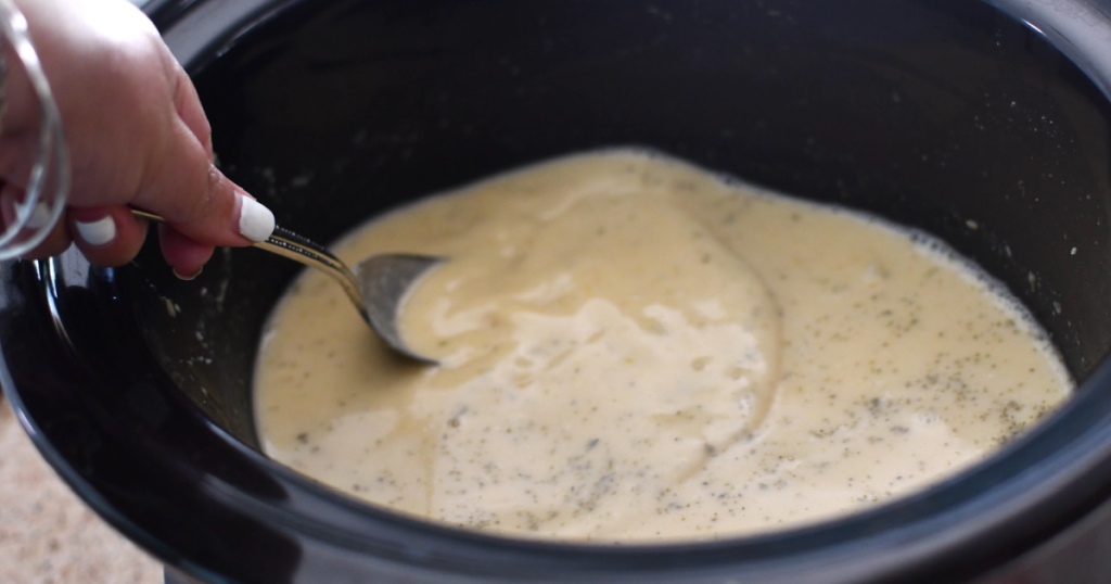 stirring butternut squash soup with a spoon in slow cooker 