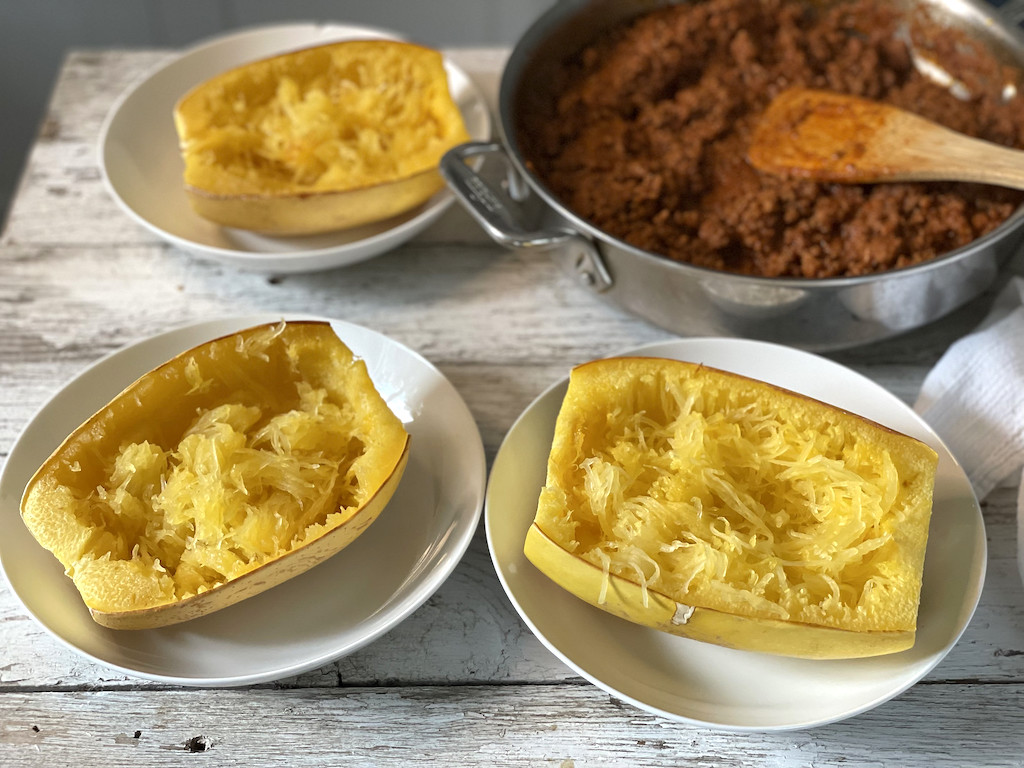 spaghetti squash on plates with ground beef in pan