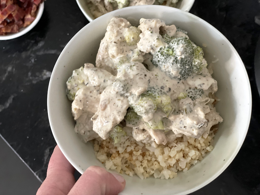 holding bowl of cream cheese chicken with cauliflower rice 