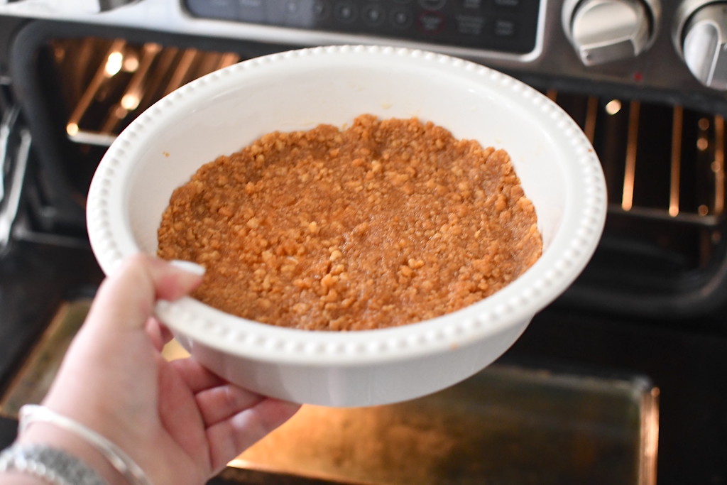 holding pie pan with keto graham cracker crust